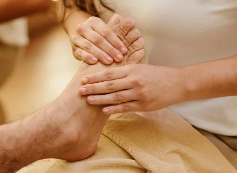 Foot reflexology showing the top of the foot with reflexologist's hands
